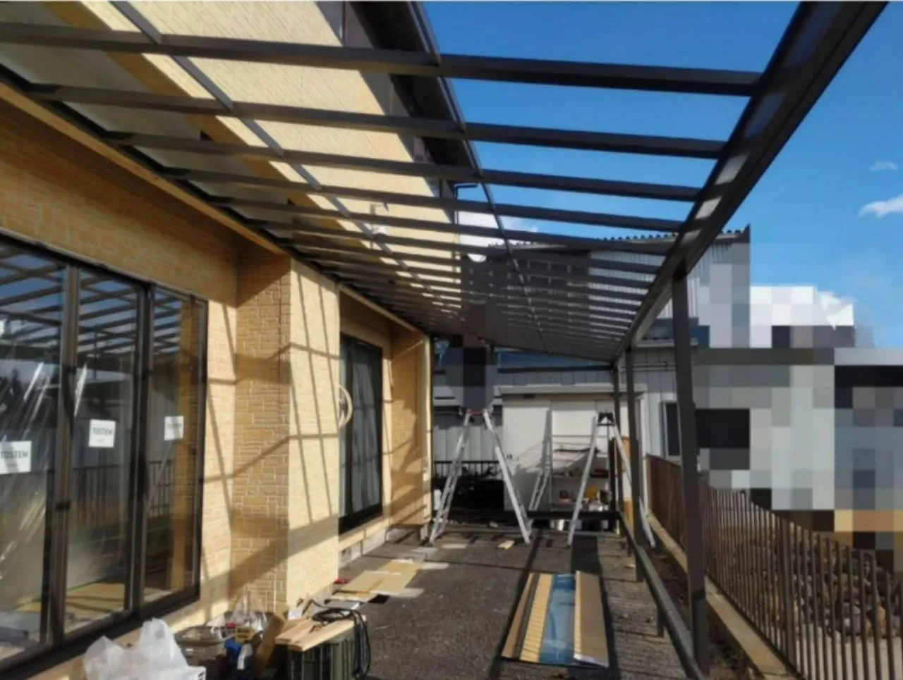 大型サンルームの柱と屋根部分を組み立てている施工中の様子。